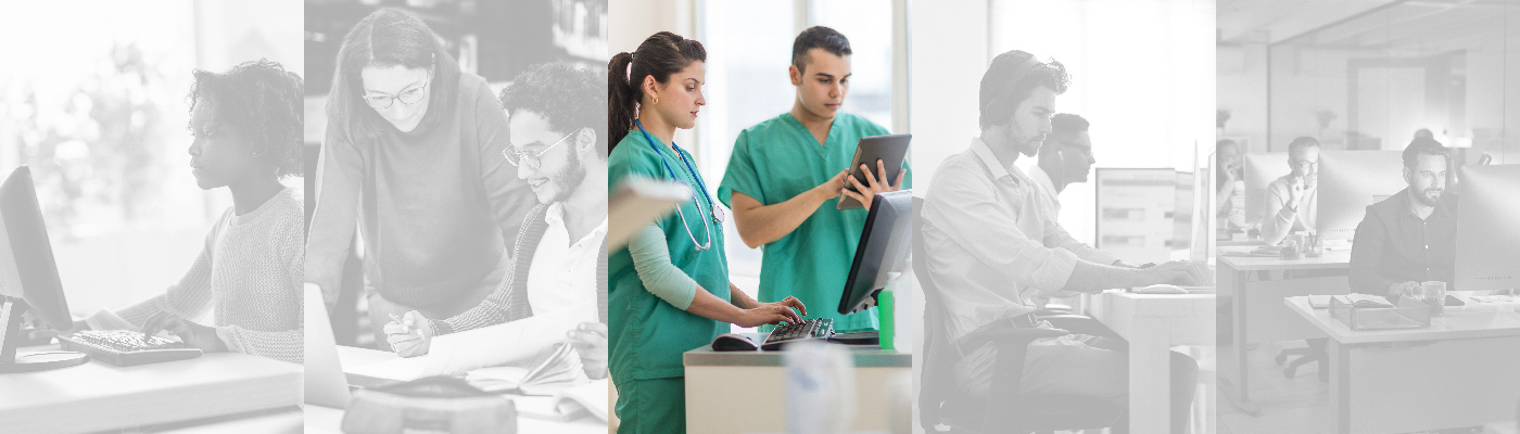 Two healthcare professionals standing side by side, one typing on a desktop computer and the other looking at a tablet