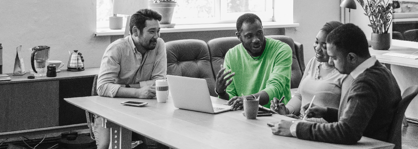 Decorative image of four people working around a table