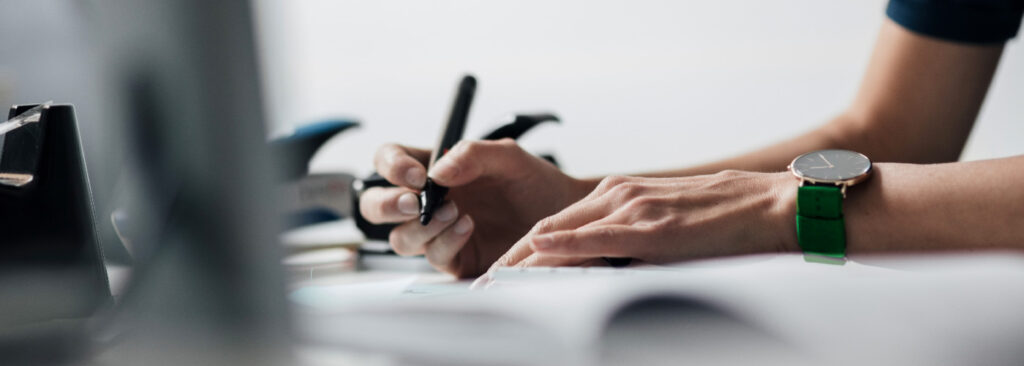 Close-up picture of a person holding a pen and preparing to write something