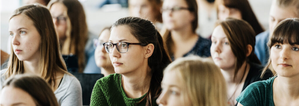 A group of students sitting in a classroom looking toward the front of the class