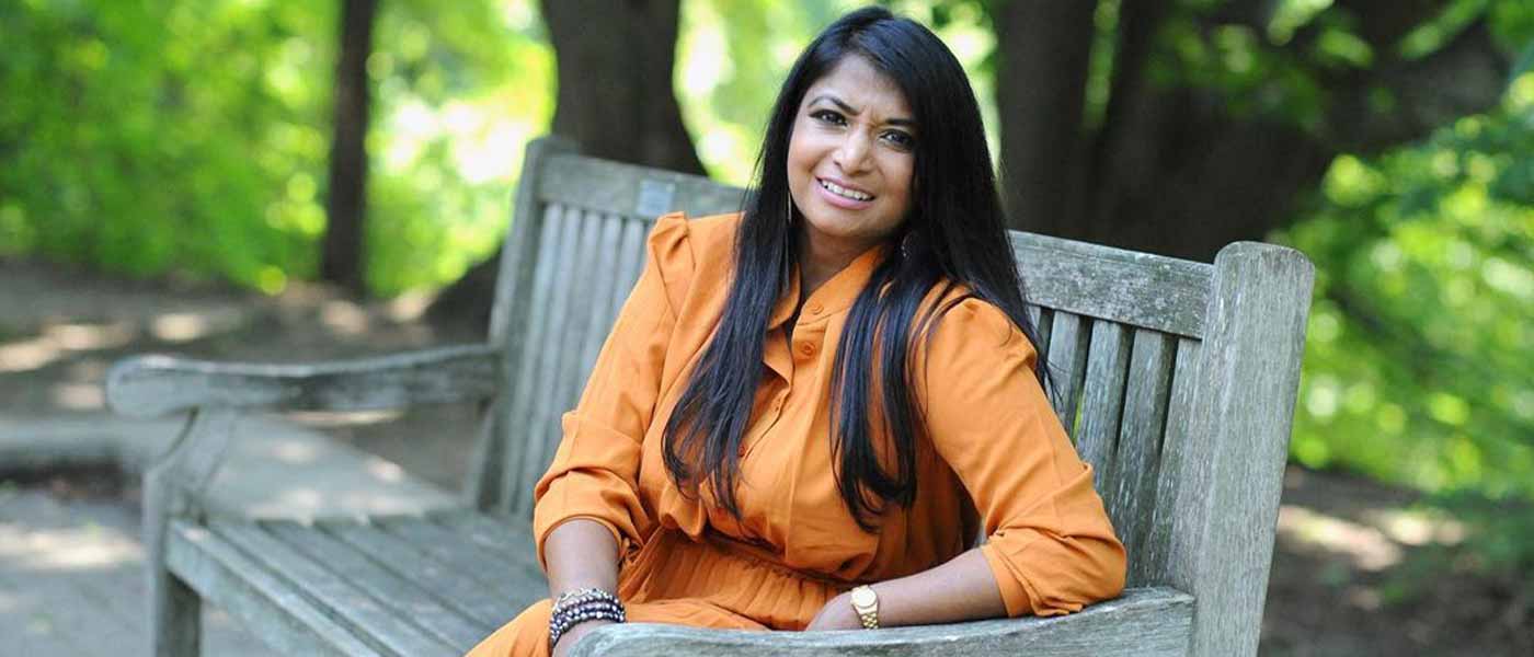 Elementary teacher Nilmini Ratwatte-Henstridge sits on a park bench smiling