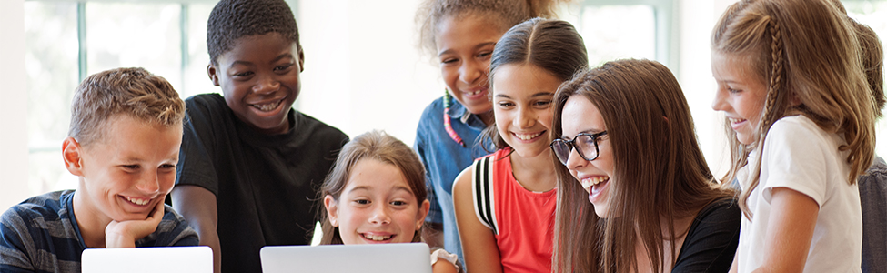 teacher with group of students around laptop
