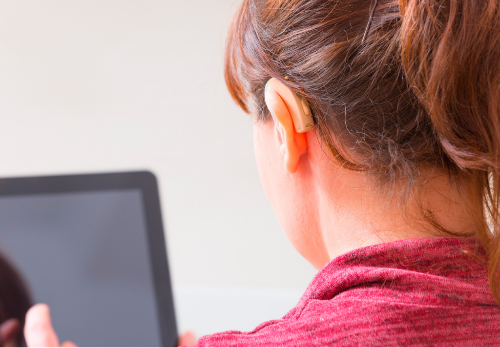 Woman wearing hearing aid looking at tablet